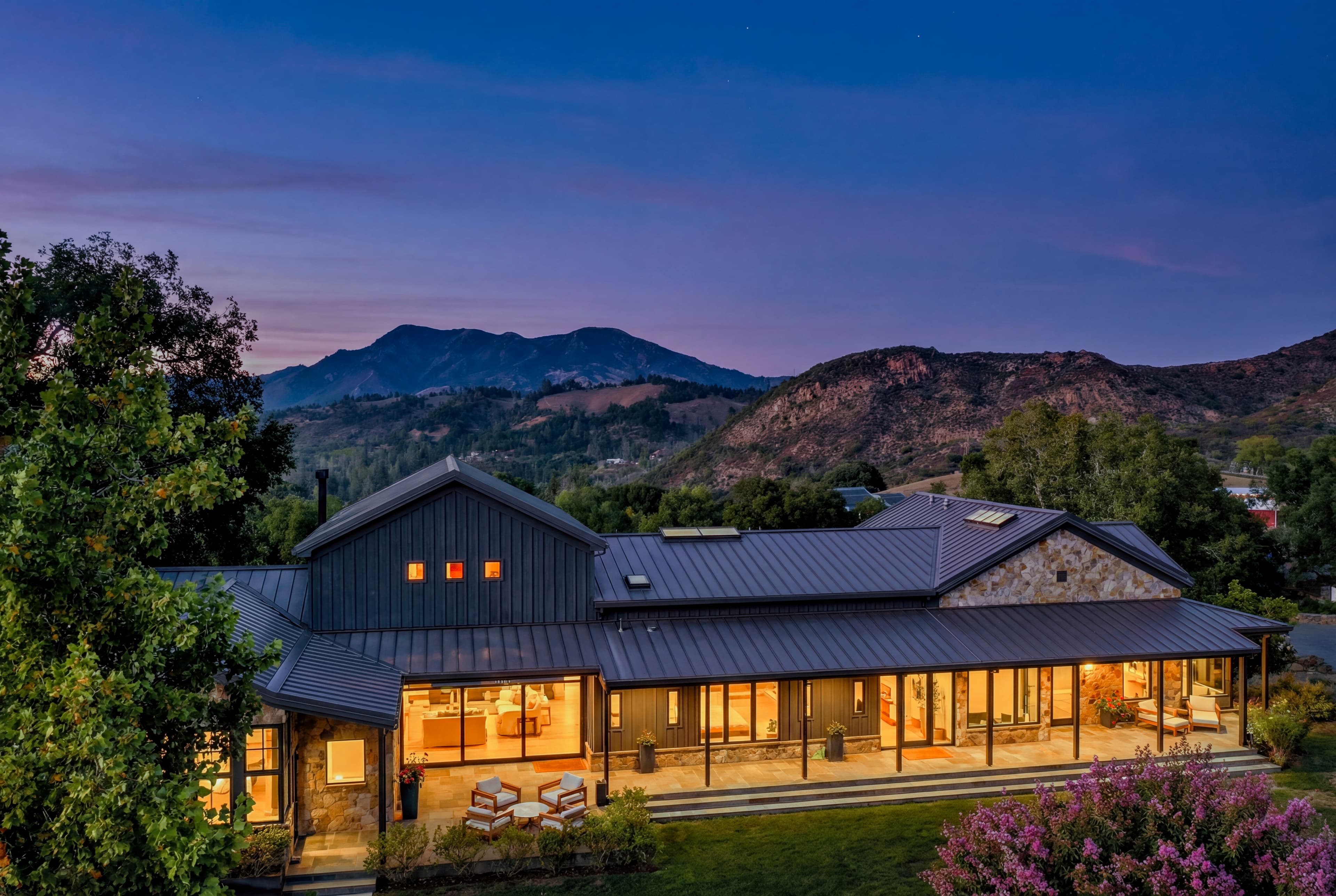 Twilight real estate photo of luxury home exterior with warm interior lights at dusk