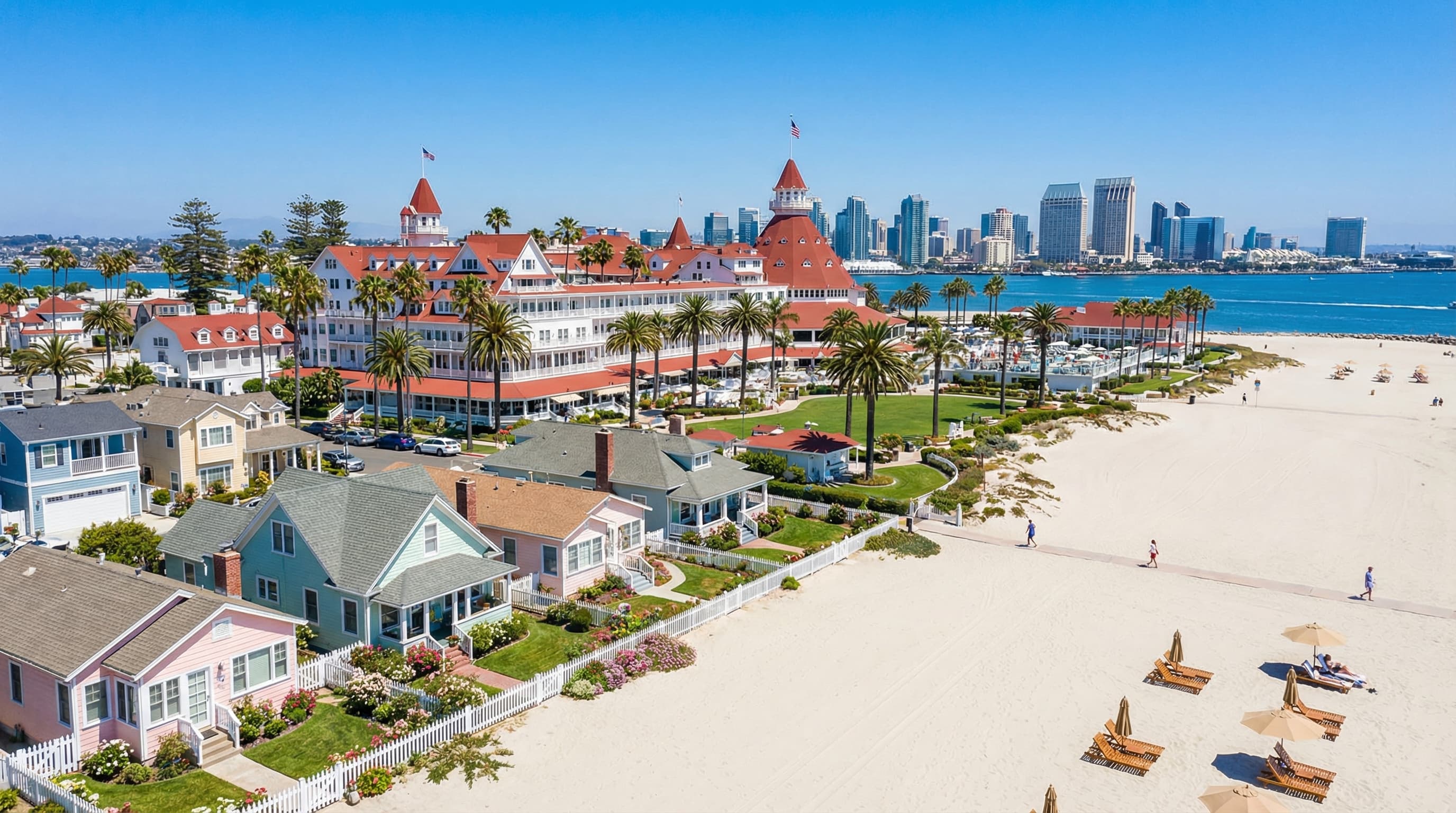 Historic Coronado California island paradise with iconic Hotel del Coronado Victorian architecture, pristine beach, elegant beach cottages, and San Diego skyline visible across bay