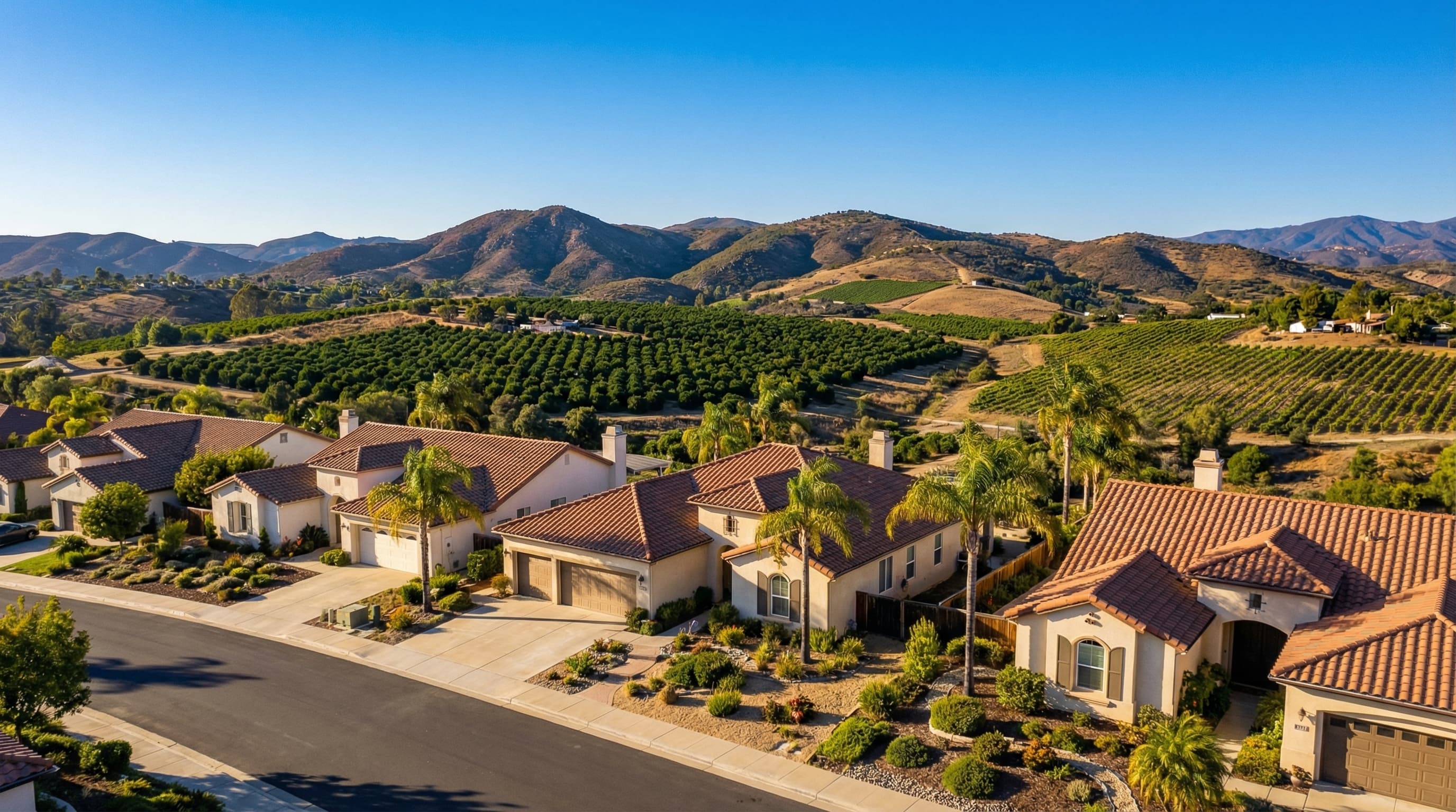 Scenic Escondido California inland residential area with single family homes, mountain backdrop, and citrus trees in surrounding hills on a bright sunny day